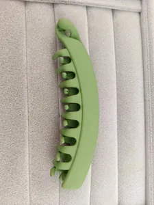 Macro view of matte grass green banana hair clip with multi-teeth grip on velvet tray