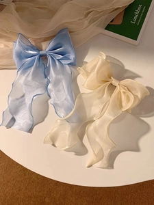 Close-up of blue and off-white organza bow hair clips with long flowing ribbons