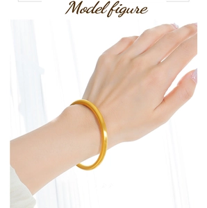 Close-up of a matte gold circular bangle worn on a wrist showing the minimalist metal texture