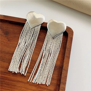 Silver heart tassel drop earrings in stainless steel on a dark wooden tray display