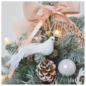 Close-up of white artificial bird, pine cone and pink bow ornaments on a Christmas tree