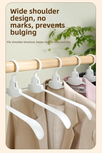 Detail of white wide-shoulder foldable hangers on a wooden rod preventing shoulder bumps