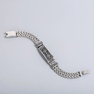 Macro detail of men's titanium steel bracelet featuring vintage totem and wheat chain