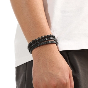 Dettaglio macro del set di bracciali da uomo in pelle nera intrecciata e pietra lavica