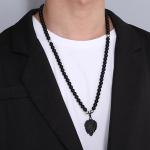 Detail of lion head pendant on black onyx bead necklace worn by a male model