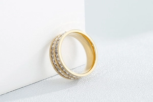 Detailansicht goldener Titanring mit zweireihigen quadratischen Zirkoniasteinen auf Block