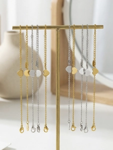 Detailed view of 18k gold heart charm bracelets hanging on a display stand in a home setting