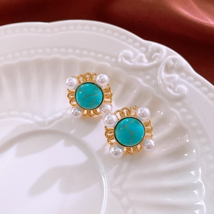 Detailed macro view of vintage gold stud earrings with turquoise gemstone and pearls