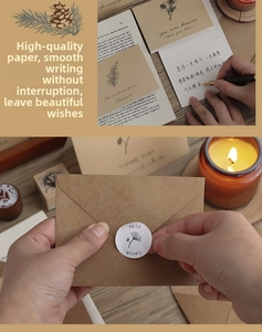 Vintage kraft envelope with white card and ginkgo leaf seal sticker on a wooden table