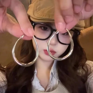 Minimalist silver oval hoop earrings held by a model for a stylish close-up presentation