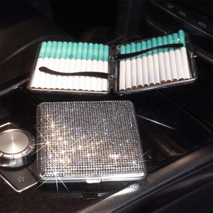 Slim stainless steel cigarette case with silver rhinestones on luxury car console