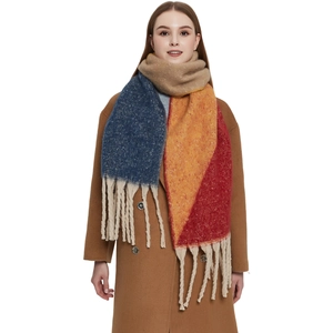 Thick colorful jacquard knit scarf with long tassels worn by a model in a studio setting