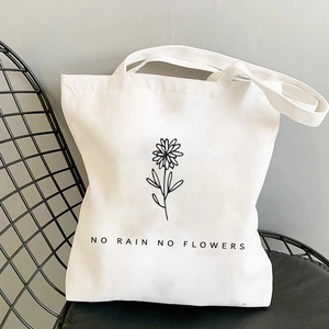 Detailed shot of white canvas tote bag with butterfly floral print on black metal chair