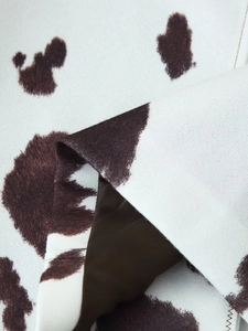 Close-up of cow print jacket fabric featuring textured outer layer and smooth brown lining