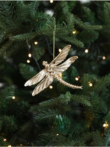 Libellula dorata di Natale con finitura metallica appesa a un ramo di albero illuminato