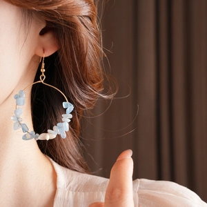 Detailed view of large gold hoop earrings with light blue and white irregular gravel stones