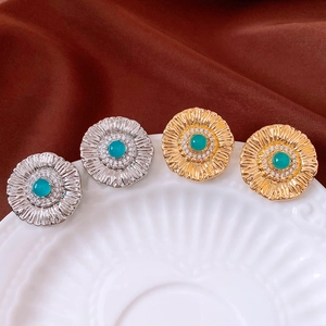 Detailed macro of vintage sunflower earrings with green gemstones and white zircon accents