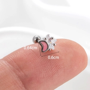 Macro shot showing dimensions of moon and star cartilage earring studs held by hand