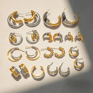 Chic gold and silver two-tone stainless steel C-shaped stud earrings set on grey surface