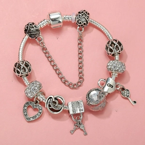Macro shot of silver charm bracelet with 'LOVE' padlock, heart and key charms