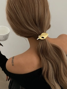 Detailed view of a golden leaf hair clip with rhinestones worn on a ponytail