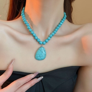 Close-up of bohemian turquoise beaded necklace with waterdrop pendant on model's neck