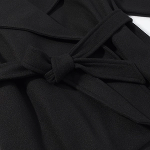 Close-up of the adjustable waist belt tie detail on a black wool coat for women
