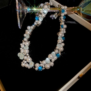 Detailed view of pearl necklace with blue cat eye stone in luxury velvet jewelry box