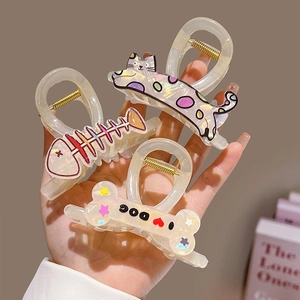 Cute cartoon cat and dog claw clips in pearlescent acetate held by a hand for children
