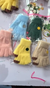 Detailed view of colorful knitted kids gloves with smiley patches in clear packaging