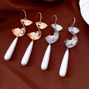 Close-up of wavy fan-shaped earrings with crystals and white textured drop charms