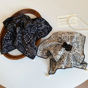 Detail of silk bandana print hair claw clips with pearls on a vintage wooden tray