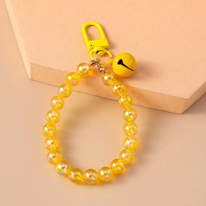 Detail of yellow pearlescent beaded keychain with metal bell pendant and clasp