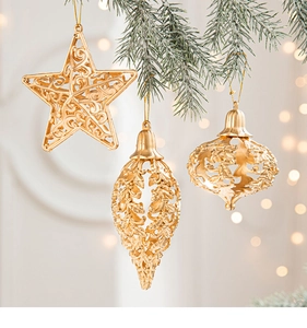 Detail of gold hollow Christmas tree ornaments on snow-covered pine branches with bokeh lights