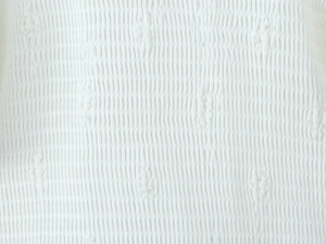 Vista macro de tela nido de abeja blanca con bordado floral intrincado y textura