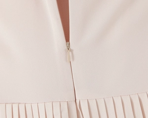 Detail of light pink pleated fabric with a seamless invisible zipper on the dress back