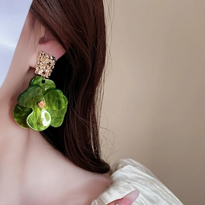 Detail of green acrylic flower earring with marble texture on model's ear
