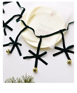 Close-up of dark green velvet bows with gold bells on elegant white plate decoration