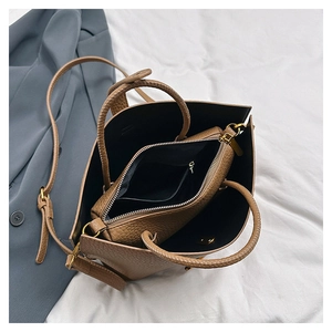 Close-up of brown litchi grain leather tote bag with inner pouch and gold hardware