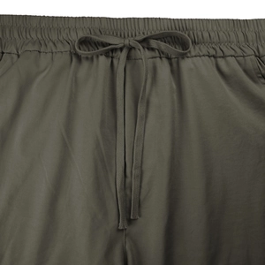 Detail of army green cargo pants featuring an elastic waistband and flat drawstrings