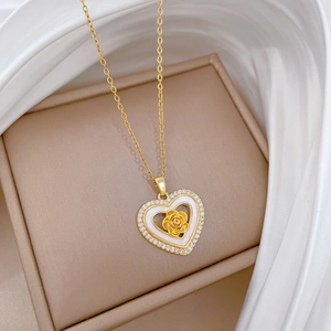 Macro detail of gold heart pendant with shell inlay, rose center and zircon border