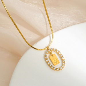 Macro view of gold-plated necklace with oval diamond frame and letter K pendant