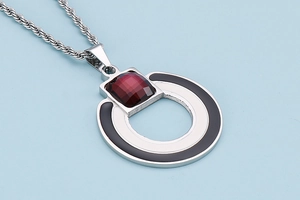 Macro shot of silver geometric pendant with black inlay and square red gemstone