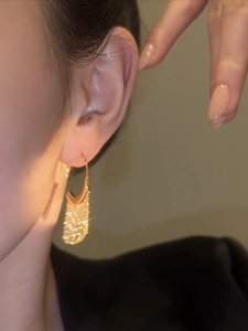 Close-up of elegant gold tassel earrings with metallic luster worn by a model
