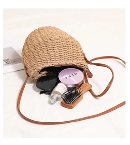 Detailed interior view of a beige shell-shaped straw bag with brown leather strap