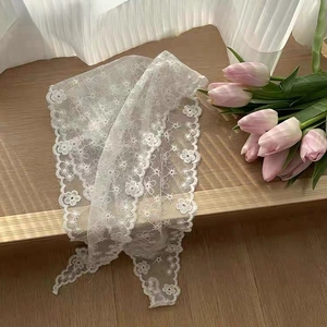 Detailed view of white floral lace triangle headscarf with delicate embroidered edges