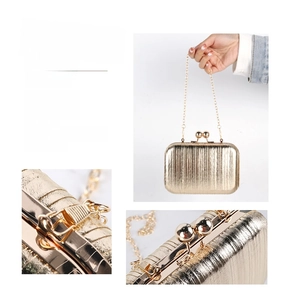 Detail of gold evening clutch with textured surface, metal chain, and ball clasp