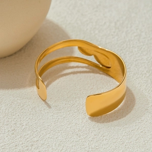 Detail of a minimalist gold stainless steel open bangle with hollow geometric design