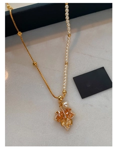 Detail of gold maple leaf pendant with amber gemstone and pearl splicing chain necklace
