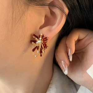 Elegant gold fireworks stud earrings with deep red glaze and sparkling zircon on model